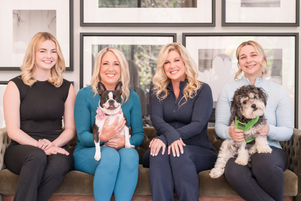 The CutiePaws team of four women sitting on a couch with a Frenchie and a small gray and white terrier